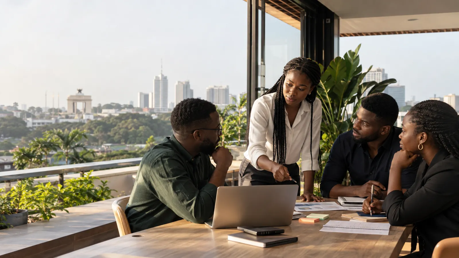 A team working around a table on a rooftop terrace overlooking Accra